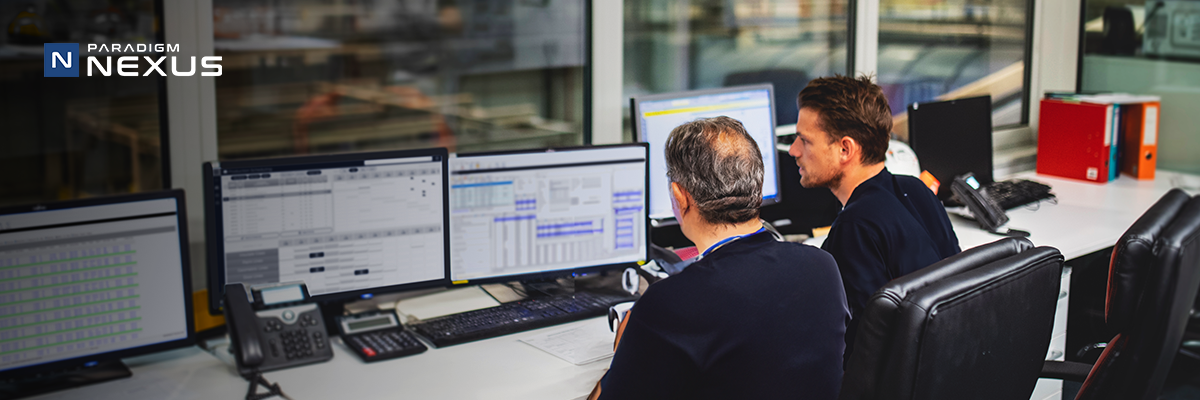 two men work together at a desk of computers