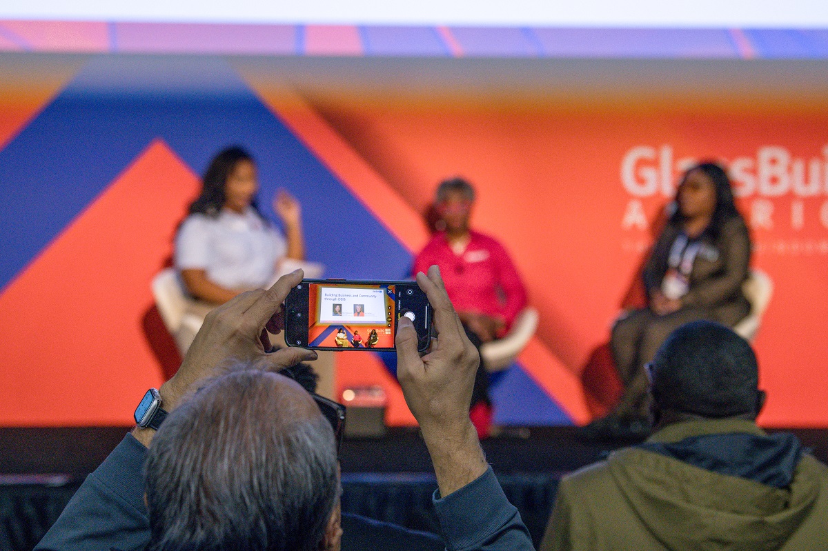 man take a photos of three presenters on the glassbuild main stage