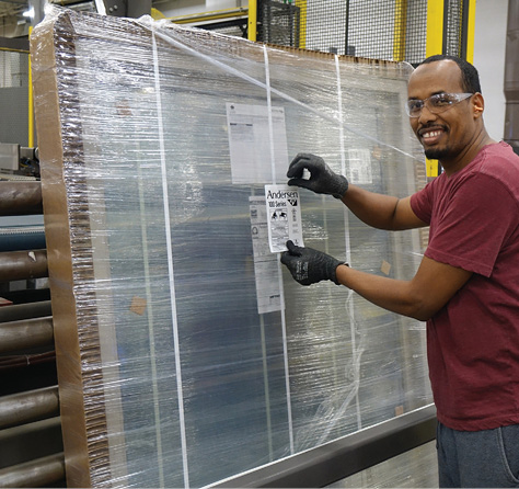 Worker at Andersen manufacturing facility handling windows