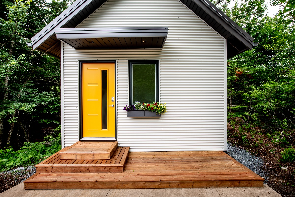 exterior of a tiny home with bright yellow door and window