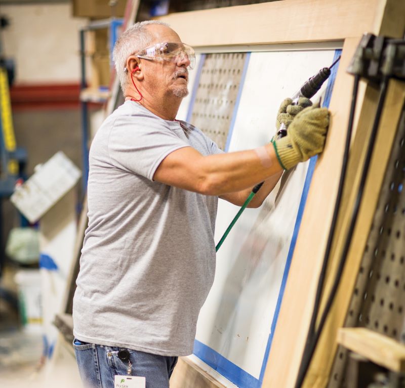 man with drill in door manufacturing facility