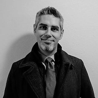 black and white photo of man with spikey hair wearing a jacket and tie