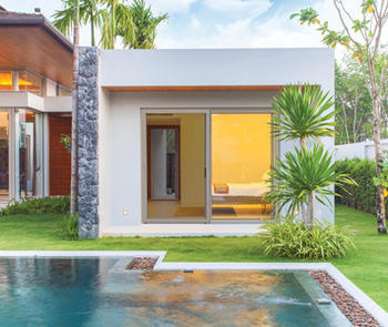 an exterior view of a sliding door with a screen on the left side facing a pool surrounded by a lawn and tropical plants