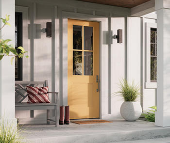 an exterior image of a white house with a front porch supported by columns and yellow entry door 