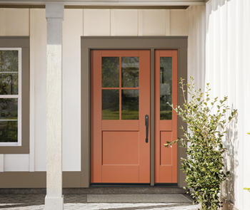 an exterior photo of a covered porch with an orange door and matching sidelite on the right with a potted plant in the foreground